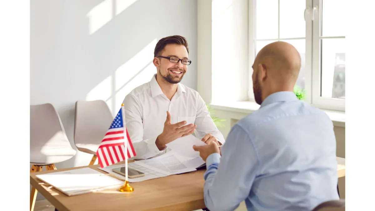 Employer meeting with an employee at a desk with a U.S. flag Employer meeting with an employee at a desk with a U.S. flag